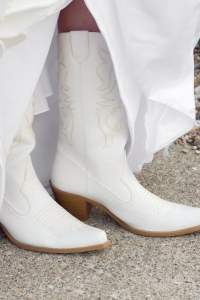 The bride wore a wedding dress and white cowboy boots.