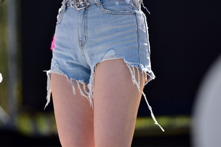Woman wears short jeans with the ripped hemline