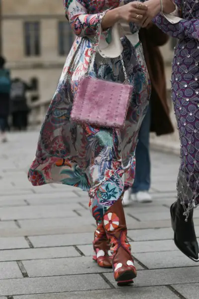 A woman wears boho dress with brown cowboy boots on the street