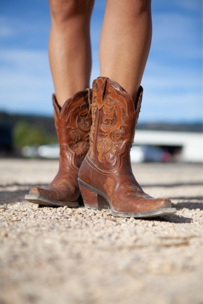 A woman wears brown cowboy boots