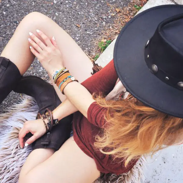 A woman wears cowboy boots with a lot of accessories for street style