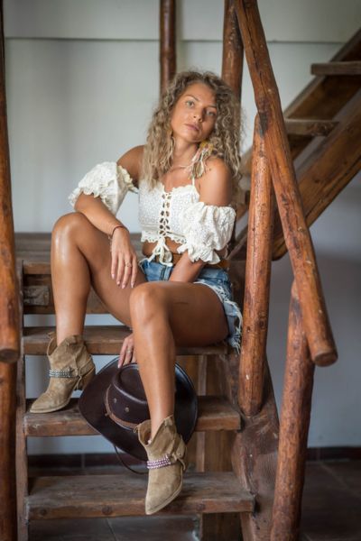 A woman wears denim shorts with cowboy boots