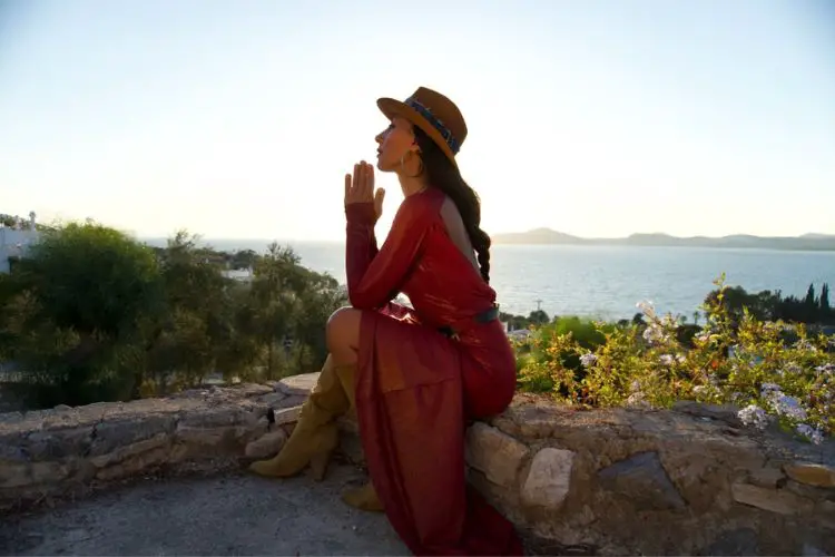 A woman wears dress, cowboy boots and hat