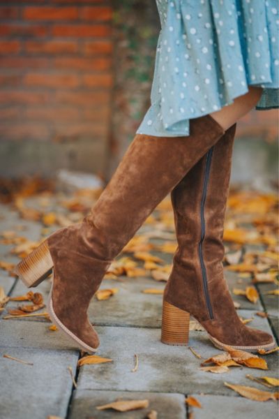 A woman wears dress with suede cowboy boots