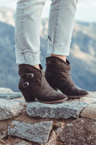 A woman wears fade jeans with ankle cowboy boots