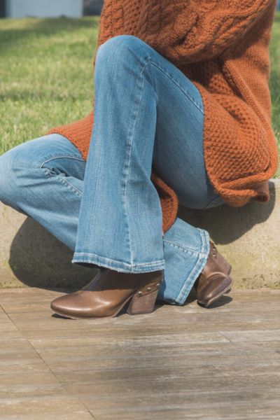A woman wears flare jeans with cowboy boots