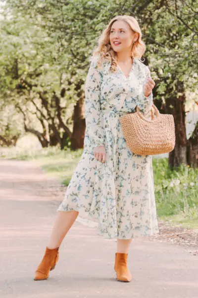 A woman wears floral dress with a pair of suede ankle cowboy boots