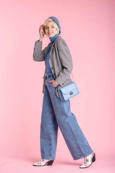 A woman wears jeans with cowboy boots and other accessories and fashionalbe top