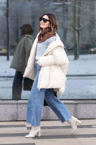 A woman wears sweater with flared jeans and wool coat