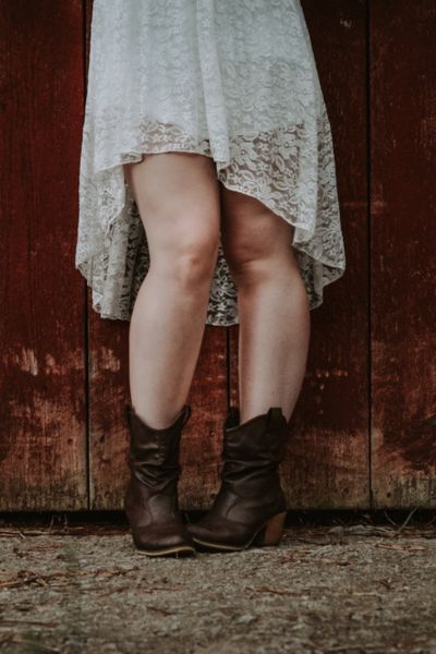 A woman wears lace dress with brown ankle cowboy boots
