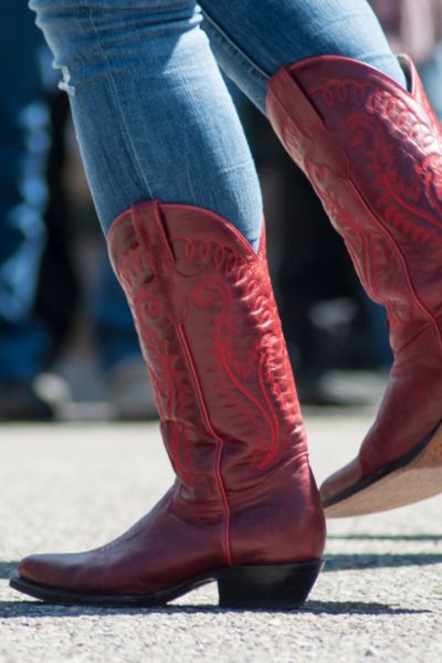 A woman wears red cowboy boots with skinny jeans