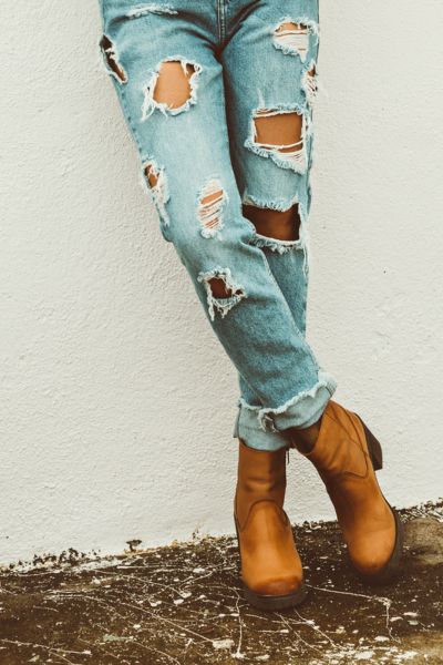 A woman wears ripped jeans with cowboy boots