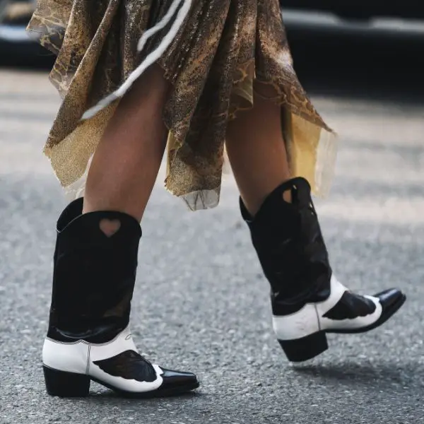 A woman wears skirt with non traditional cowboy boots