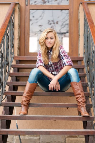 A woman wears tight fit cowboy boots with skinny jeans and plaid shirt