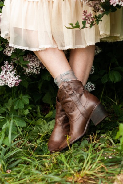 A woman wears white dress or skirt with cowboy boots
