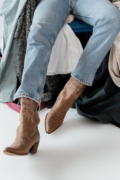 A woman wears wide leg jeans with a pair of traditional cowboy boots.