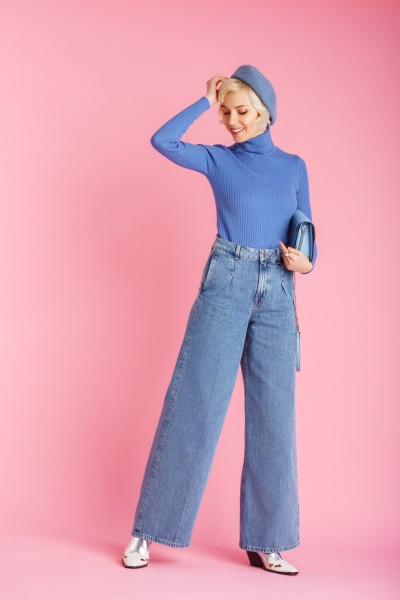 A woman wears wide leg jeans with a turtleneck sweater and cowboy boots