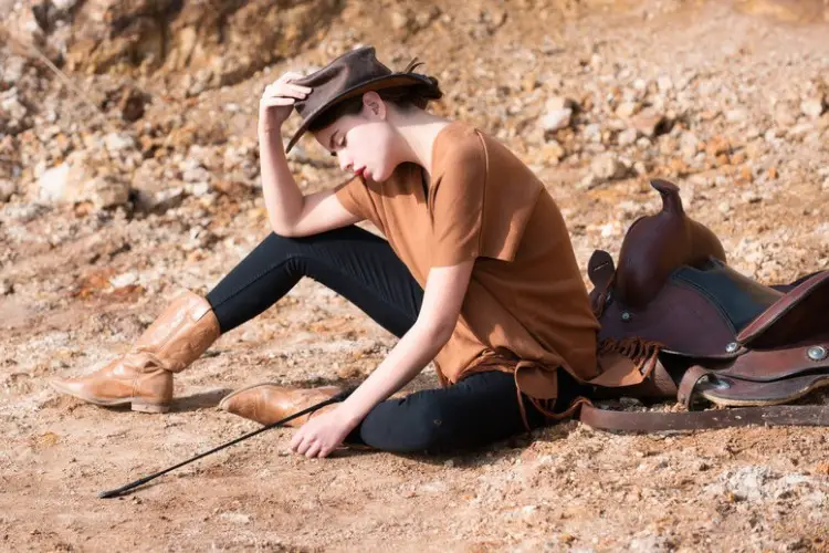 a woman wears brown cowboy boots and jeans on the ranch