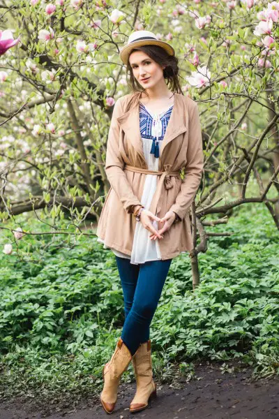 a woman wears jeans with cowboy boots, blazer and shirt underneath