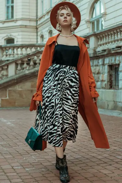 A woman wear zebra skirt with trench coat and cowboy boots