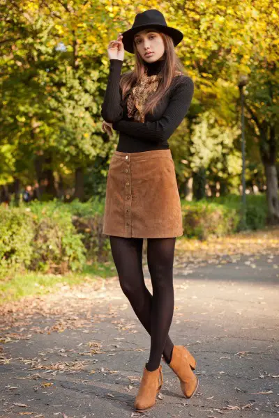 A woman wear suede skirt, cowboy boots with tight fitted t shirt and tights