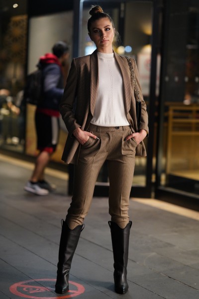 A woman wears black cowboy boots with suits and white top