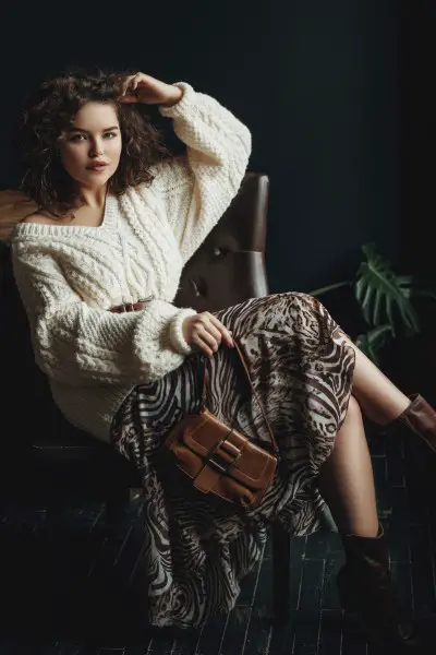 A woman wears brown cowboy boots with sweater and zebra skirt