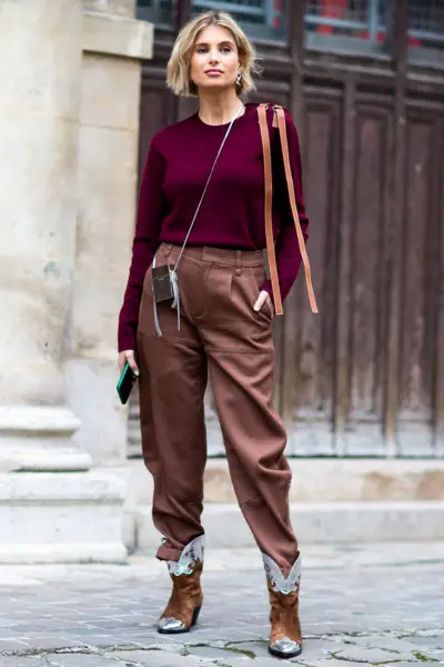 A woman wears brown pants, cowboy boots and dark red sweater