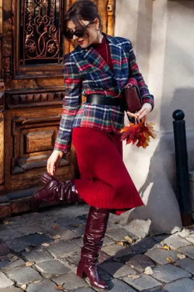 A woman wears cowboy boots with red dress and blazer suit