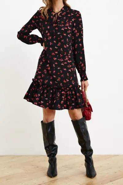 A woman wears floral dress and black cowboy boots