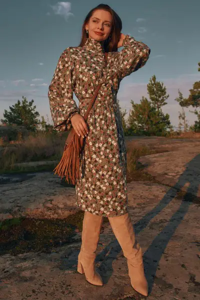 A woman wears floral dress with cowboy boots