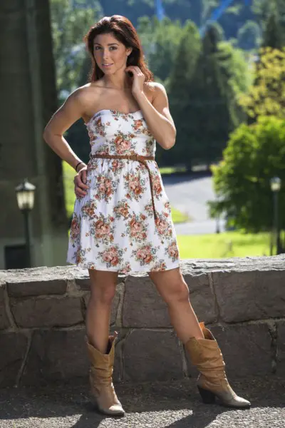 A woman wears floral dress with cowboy boots