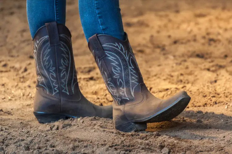 A woman wears jeans with cowboy boots on the ranch