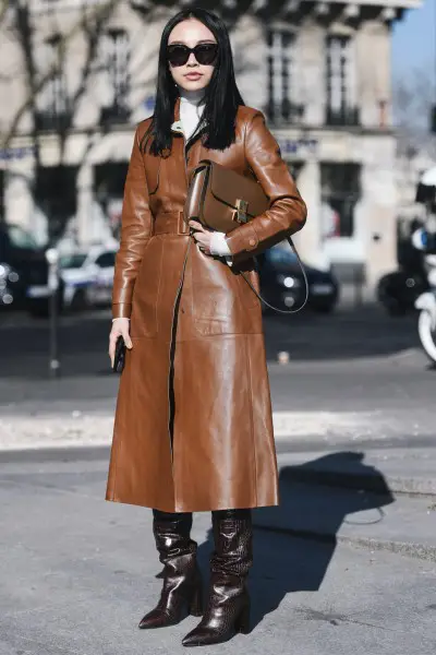 A woman wears leather trench coat with cowboy boots