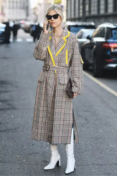 A woman wears trench coat with cowboy boots