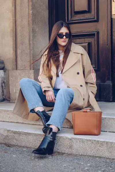 A woman wears trench coat with jeans and cowboy boots