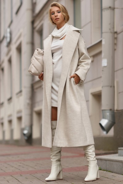 A woman wears white dress, cowboy boots and blazer