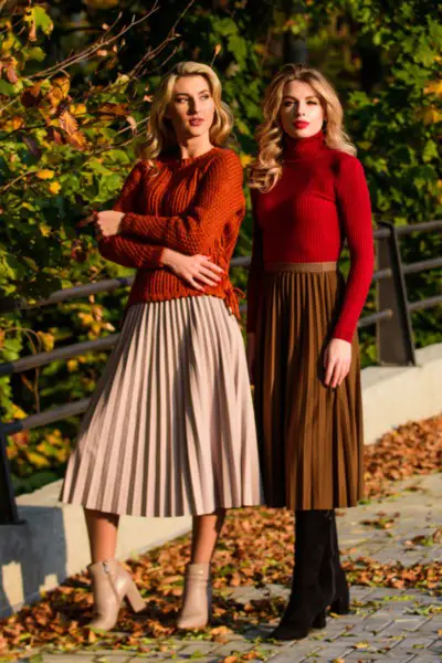 Women wear pleated skirt with cowboy boots and sweater