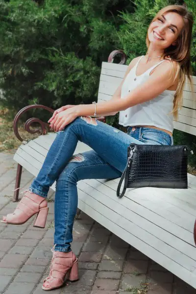 A woman wears ankle boots with jeans and 2 strap tee.