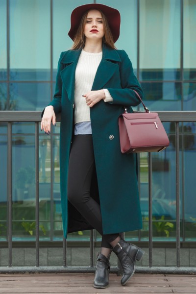 A woman wears ankle boots with trench coat, leggings and handbag