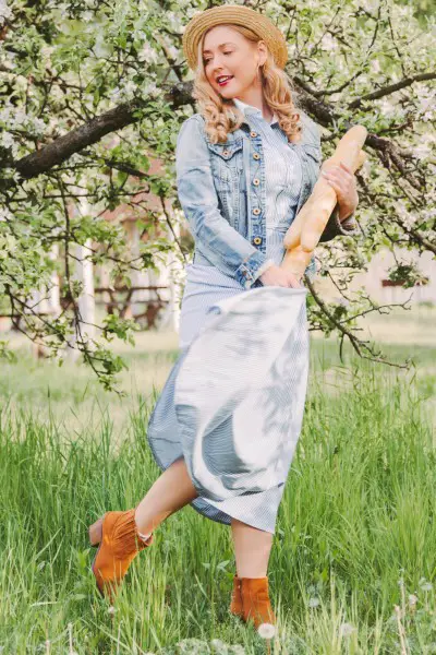 A woman wears ankle cowboy boots with denim jacket and dress
