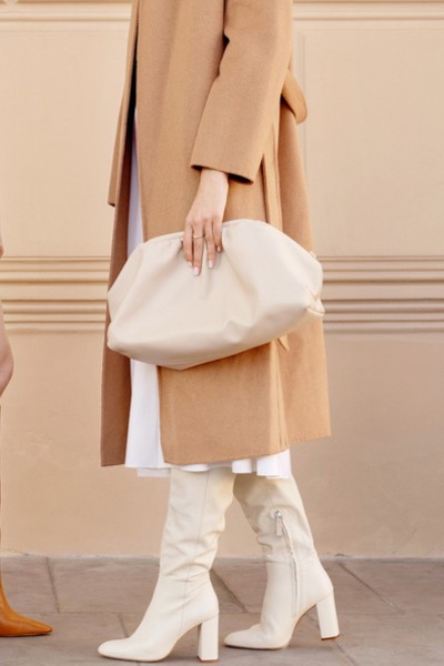 A woman wears beige blazer and white cowboy boots