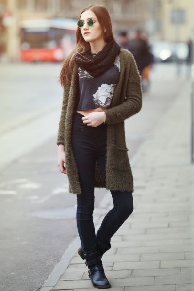 A woman wears black ankle cowboy boots, jeans and cardigan