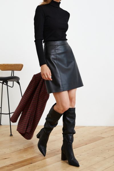 A woman wears black cowboy boots with black leather skirt and black sweater