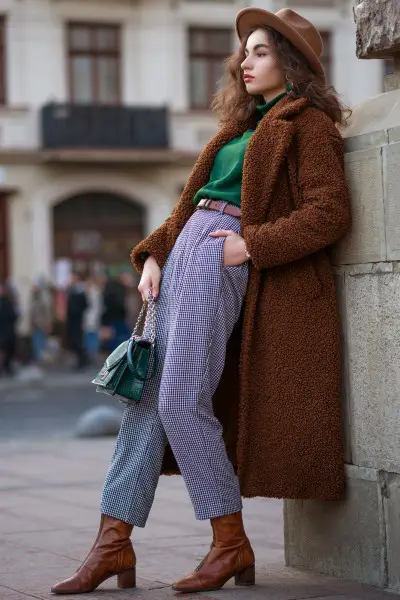 A woman wears brown cowbo boots, fur coat with purpose pants and green top 2