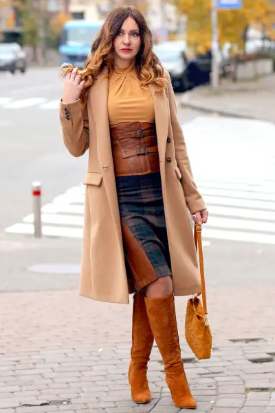 A woman wears brown cowboy boots with sleek pencil skirts and blazer for business style.