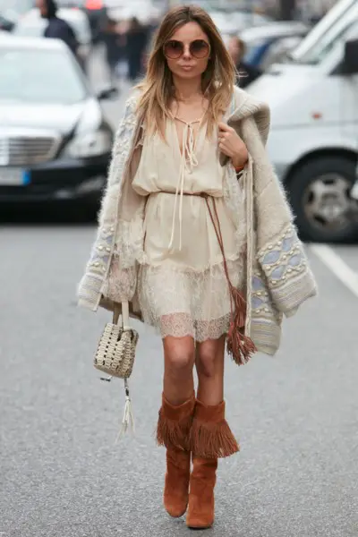 A woman wears cowboy boots, dress and coat in boho style