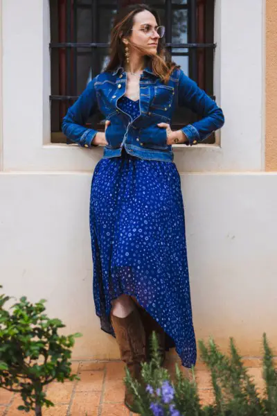 A woman wears cowboy boots with blue long dress and denim jacket