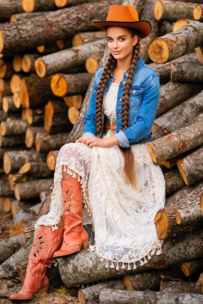 A woman wears cowboy boots with lace dress, denim jacket and cowboy hat