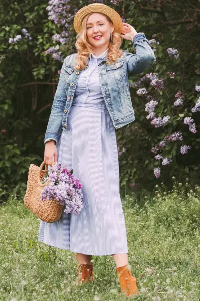 A woman wears dress with ankle cowboy boots and denim jacket